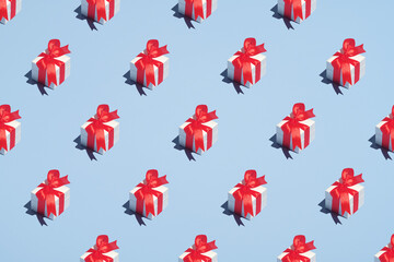 Pattern with gift boxes decorated red ribbon bows on blue background. Christmas, winter holidays, New year concept. Minimal style.