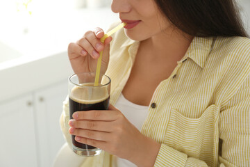 Young woman with cold kvass indoors, closeup. Traditional Russian summer drink