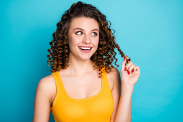 Photo of lovely dreamy student girl excited look empty space play curl funny wear yellow singlet isolated blue color background