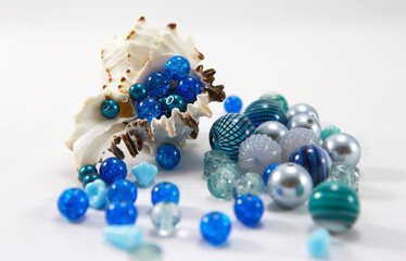 Round blue beads in a sea shell on a white background