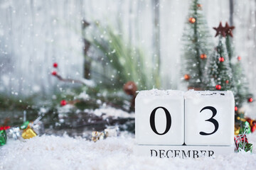 Giving Tuesday or National Disability Day. White wood calendar blocks with the date December 3rd and Christmas decorations with snow. Selective focus with blurred background. 