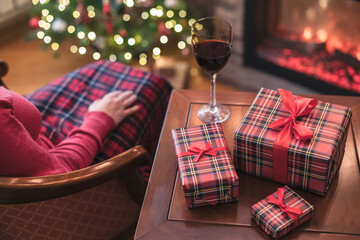 Alone woman covered plaid with glass of wine sitting and relaxation on armchair near fareplace and...