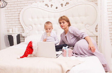 A boy with Down syndrome and a disability sits with his mother on the couch, online video greetings...