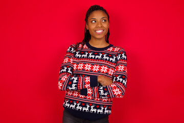 Dreamy rest relaxed Young beautiful African American woman standing against red background crossing arms, looks good copyspace