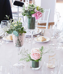 Detail of a wedding table with bouquet of pink roses and green leaves as decoration