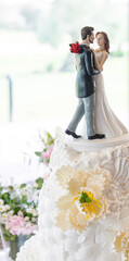 Detail of a pretty just married couple figure on the top of a beautiful wedding cream cake...