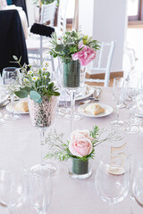 Detail of a wedding table with bouquet of pink roses and green leaves as decoration