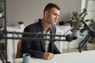Young man sitting at the table and speaking in microphone giving an interview on radio