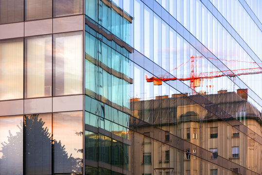 Old building and crane reflection in modern office building glass wall