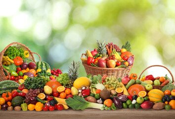 Assortment of fresh organic vegetables and fruits on wooden table against blurred green background