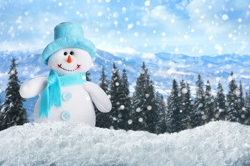 Cute toy snowman in winter forest. Space for text