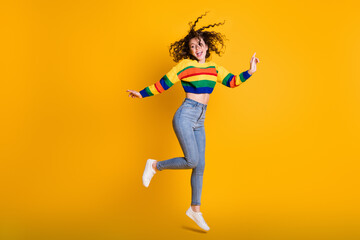 Fototapeta na wymiar Full length photo of funny jumping lady wearing casual colorful sweater dancing pointing looking empty space isolated yellow color background