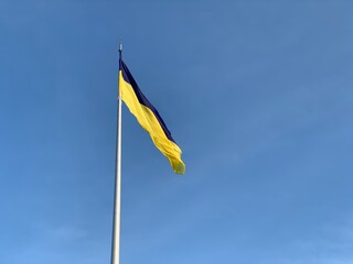 Flag of Ukraine on a background of blue sky. National flag on a flagpole. Ukrainian symbols.