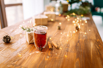 Glass mug of black tea on the wooden festive table