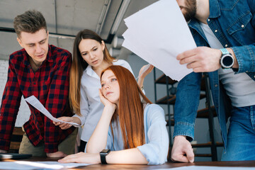 Low-angle shot of exhausted overworked young business woman under stress at office. Colleagues...