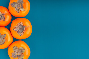 Top view of persimmons on a blue background with copy space for text. Concept of health fruit