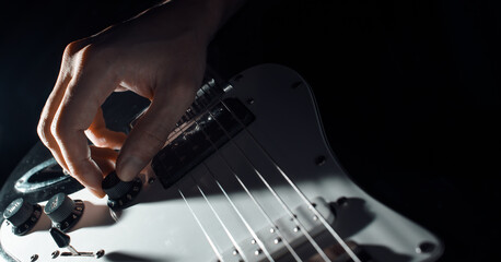Musician playing the electric guitar. Close-up of a man's hand turning the volume slider on the...