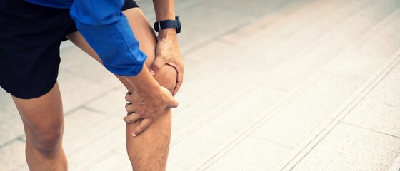 A man wearing a blue Windbreaker jacket., Knee pain after exercise concept.It happens often in...