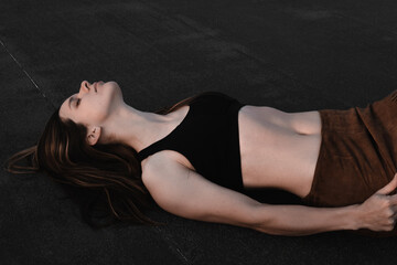 
A girl in a tank top is lying on the ground