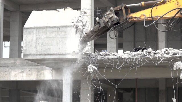 Excavator machine with hydraulic crashers at demolition of the house. House being demolished by special machinery. Slow motion