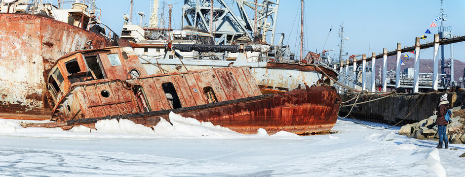Old abandoned ship in the Sea of Japan. Rusty ship, frozen in the ice on the coast. Background with abandoned rusty ship for photoshop and design. Small overturned rusty broken fishing ship