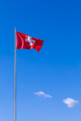 Waving Switzerland flag against blue sky (Vertical photo)