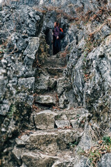 Long stone staircase with woman on the top step. Stone staircase carved at the foot of the mountain in Russia. Abstract background with girl and staircase for site design and travel blog