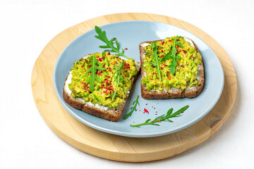 Set sandwiches for breakfast - slice of whole grain dark bread, cream cheese, guakomole, garnished with arugula, paprika on wooden table Top view Flat lay Healthy food concept Homemade