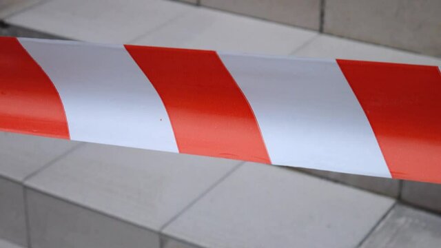 Red-and-white warning tape marks off an unsafe route, background