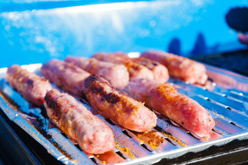 Sausages meat grilling on gas grill