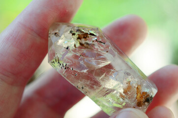 Clear quartz being held in woman's hand. Clear quartz point in the sunlight. Healing quartz with inclusions, intricate details. 
