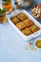 Baklava, Middle eastern different delights, dried dates, pistachios, honey, mint tea on a light blue background. Ramadan.