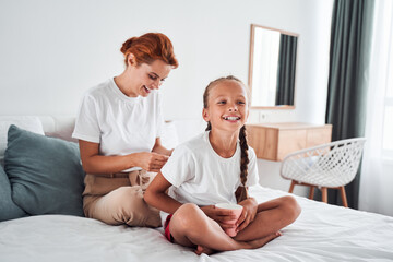 Mom making braids for her daughter