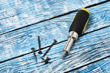 Screwdriver, screws and wooden bars on wooden background