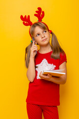 Pensive little girl writing a letter to Santa