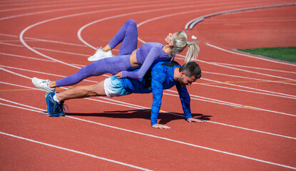 sport fitness couple training together stand in plank and do push up on outdoor stadium racetrack wearing sportswear, sport and strength