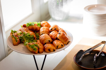 Chocolate puff pastry buns on restaurant buffet catering table. Catering buffet table with a delicious food. Stacks of croissant sandwich at wedding
