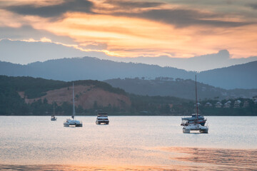 Sailing boat on a calm lake with sunset sky.