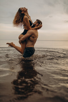 Romantic photo session in the water. A guy and a girl swim in the lake in the evening. Beautiful sunset.