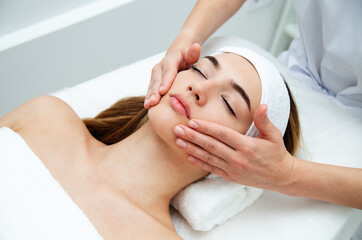 Beautician massaging woman's face. Attractive girl having facial treatment and massage. The young...