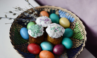 A large festive dish with Easter colored eggs, Easter cakes and pussy willow branches. Easter attributes of the holiday.
