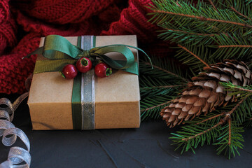 Christmas composition with gift, fir and red knitted blanket on dark background. Christmas postcard