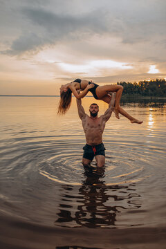 Romantic photo session in the water. A guy and a girl swim in the lake in the evening. Beautiful sunset.