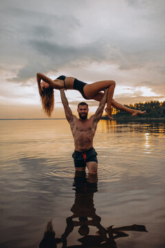 Romantic photo session in the water. A guy and a girl swim in the lake in the evening. Beautiful sunset.