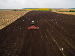 Harvesting in the field. Aerial view. Land cultivation with a tractor