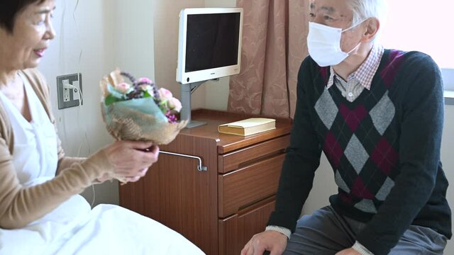 入院中の妻の見舞いに来たマスクをした夫