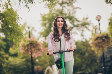 Photo of beautiful young happy girl curly hair ride electric scooter fun enjoy outside wear casual outfit