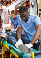 Ambulance team laying patient on stretcher in ambulance car © JackF