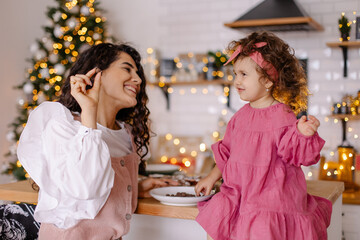 Mother and daughter are playing in kitchen at Christmas. Cooking holiday cookies. New Years morning breakfast. Sweet motherhood and childhood. Lifestyle moments of life at home. Hug happiness together