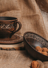 Handmade ceramic craft ware. Rustic napkin and kitchen tools. Plate on a wooden stand with nuts. Handmade ceramic dishes